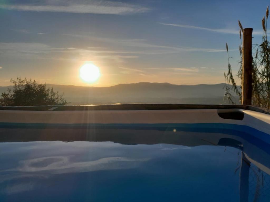 uma piscina com um pôr-do-sol ao fundo em La sosta di Fano em Reggello