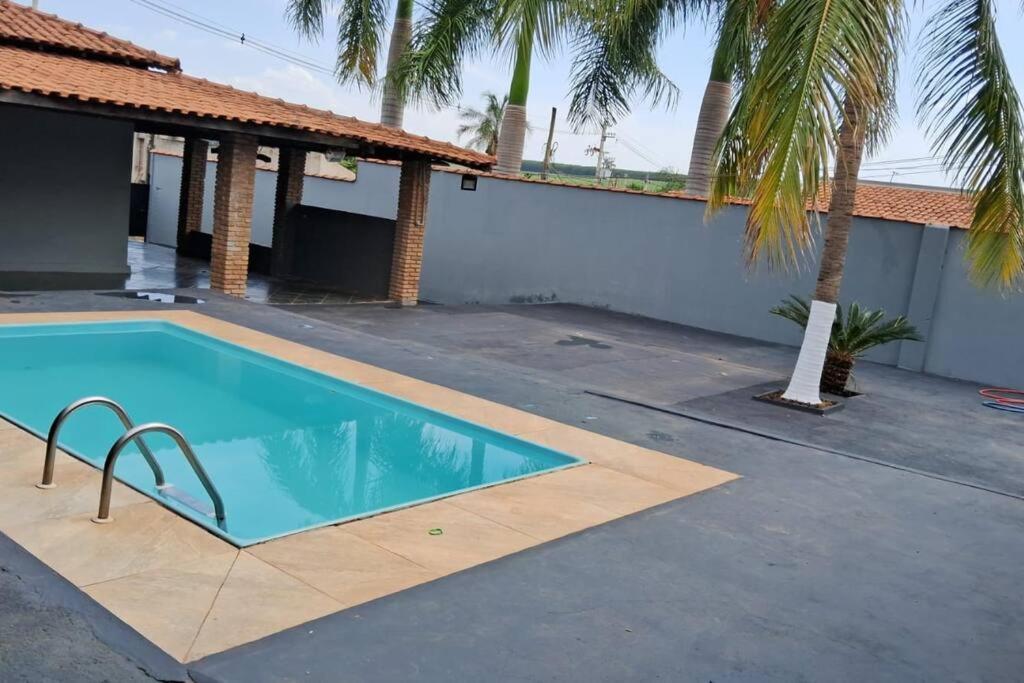 una piscina accanto a una casa con una palma di Chácara Martins a Olímpia