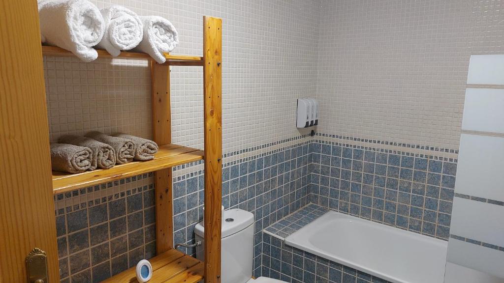 La salle de bains est pourvue de carrelage bleu, d'une baignoire et de toilettes. dans l'établissement El Nido de Candeleda, à Candeleda