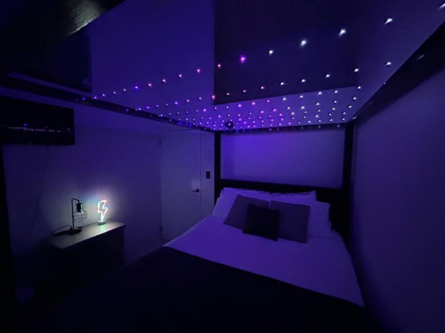 a purple bedroom with a bed and a table with a lamp at City Dreams Cozy Loft in Guayama Great Location in Guayama