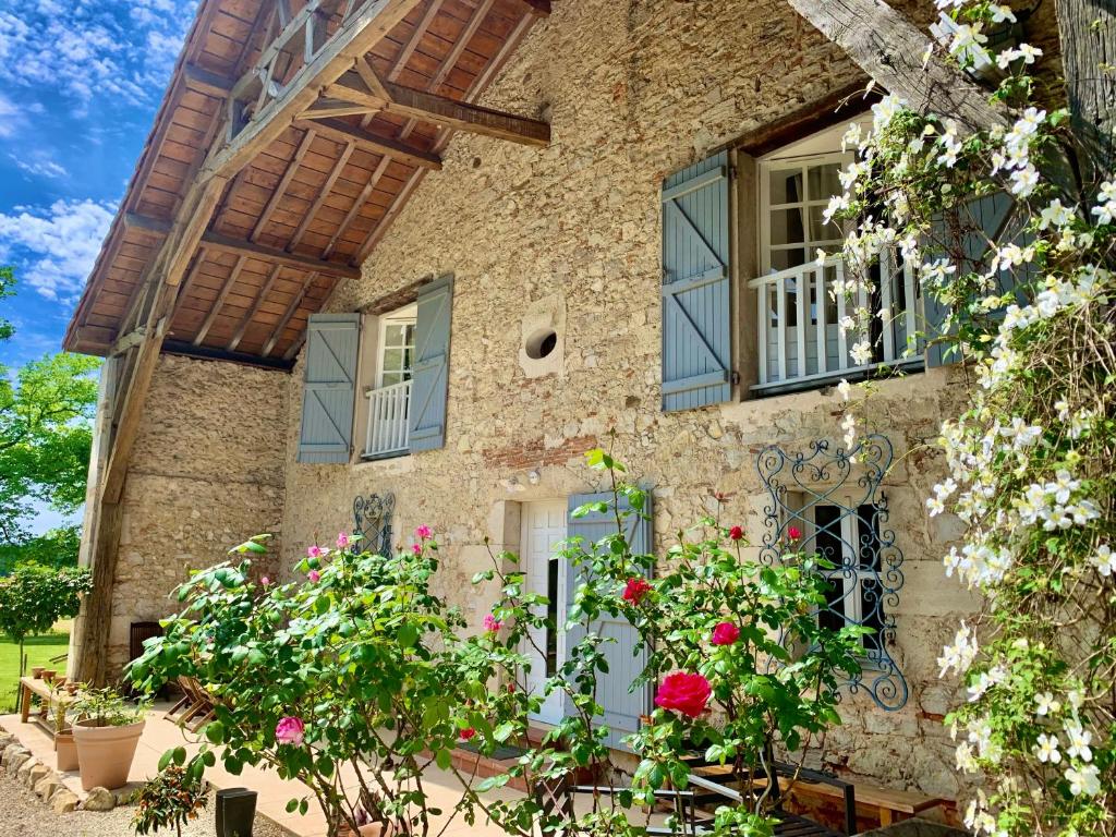 une maison en pierre avec des fleurs devant elle dans l'établissement Le Poutic piscine chauffee, à Créon-dʼArmagnac