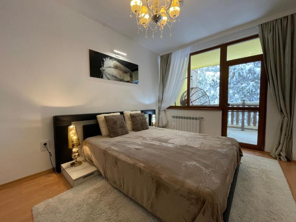 a bedroom with a large bed and a chandelier at Luxury Apartament in "Sequoia" 2 in Borovets