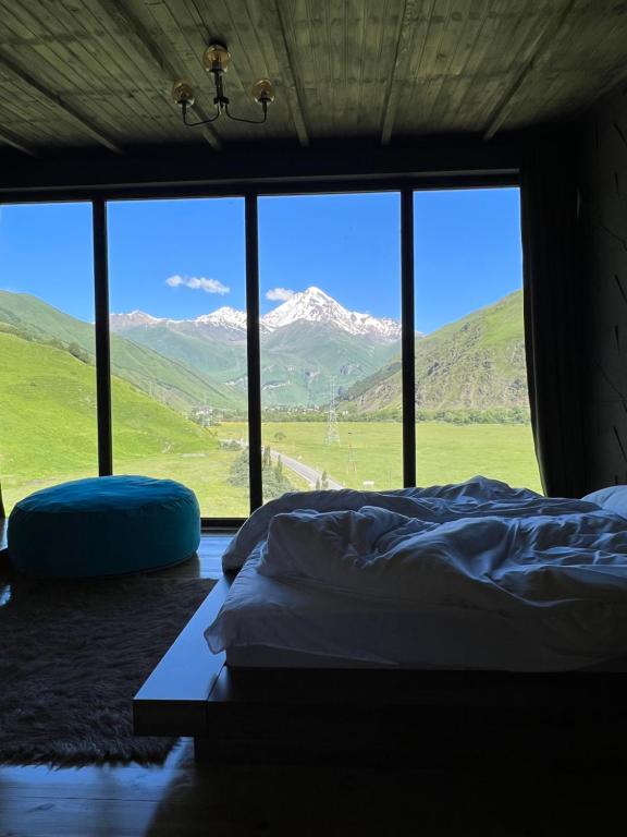 a bedroom with a bed and a view of mountains at Gzaze in Stepantsminda