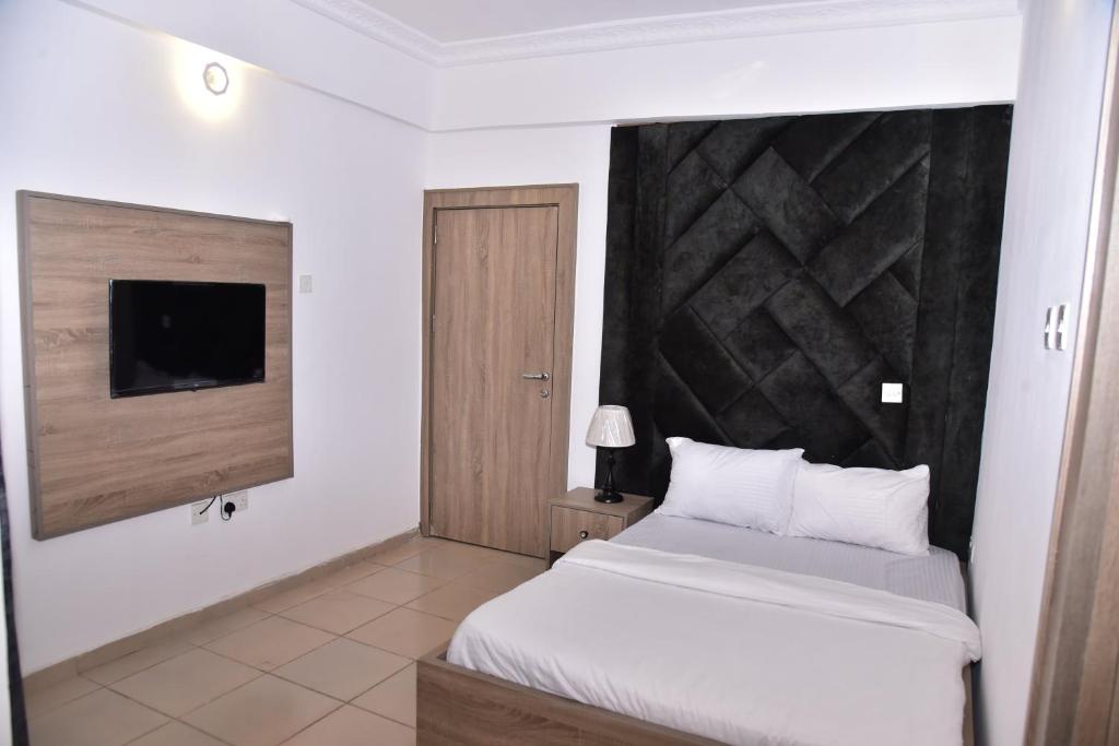 a bedroom with a white bed and a television at 1118 Serenity Residence in Abuja