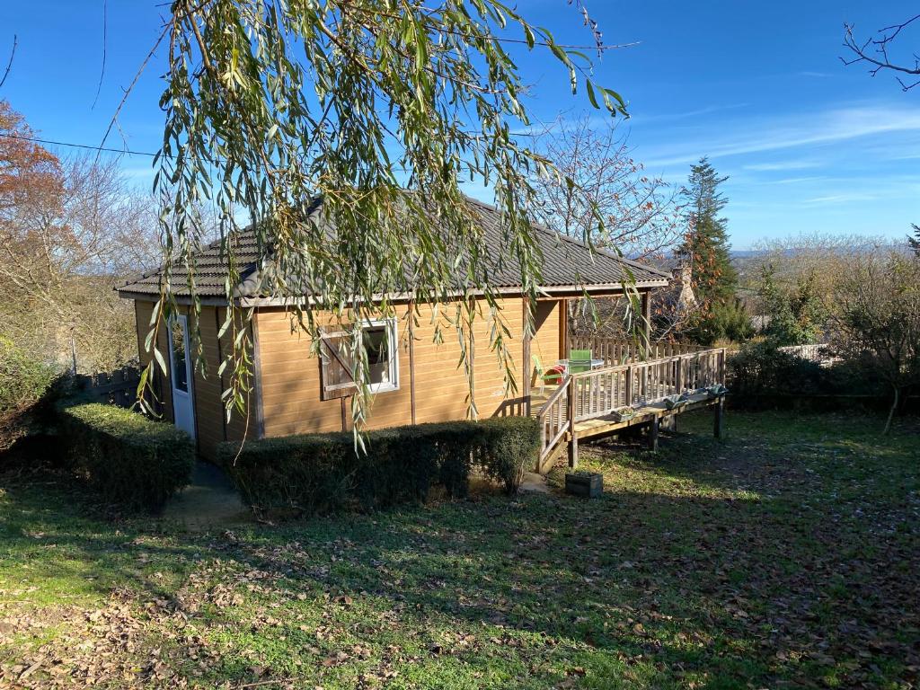 a log cabin with a porch and a tree at Charmant logement à la campagne, au calme in Manhac