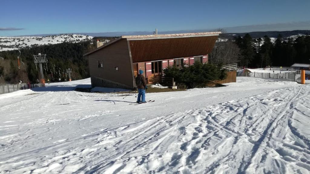 une personne à skis dans la neige devant un bâtiment dans l'établissement chalet le pastoral, à Saint-Anthème