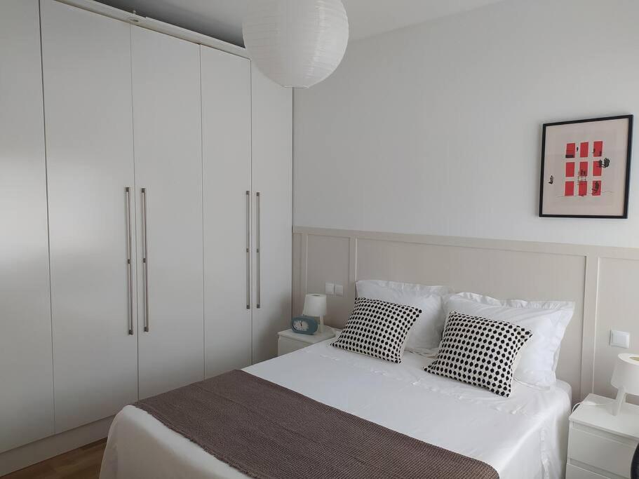 a white bedroom with a bed with two pillows at Casa Golf49 con parking in Badajoz