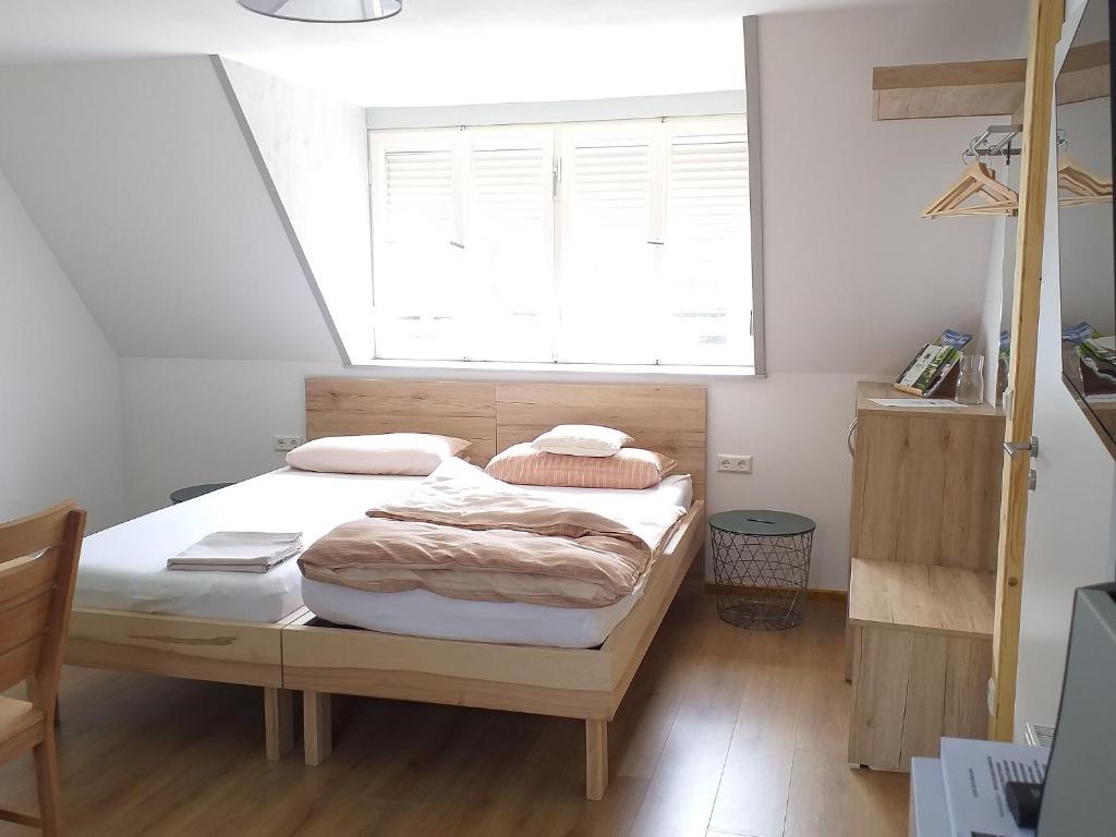 Bett in einem Zimmer mit einem großen Fenster in der Unterkunft Landcafe SIMA & Zimmervermietung in Forheim