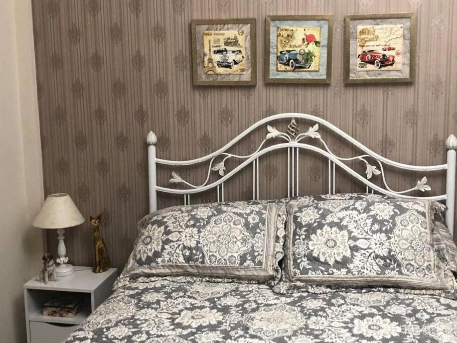 a bedroom with a white bed with three pictures on the wall at Apartamento Fontana di Trevi Centro Serra Negra in Serra Negra
