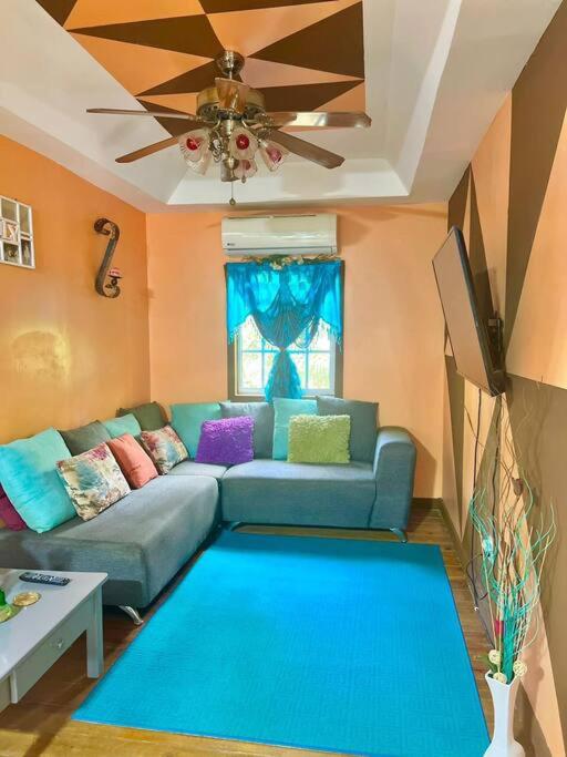 a living room with a blue couch and a ceiling fan at Island style home, low key rental in Roatan