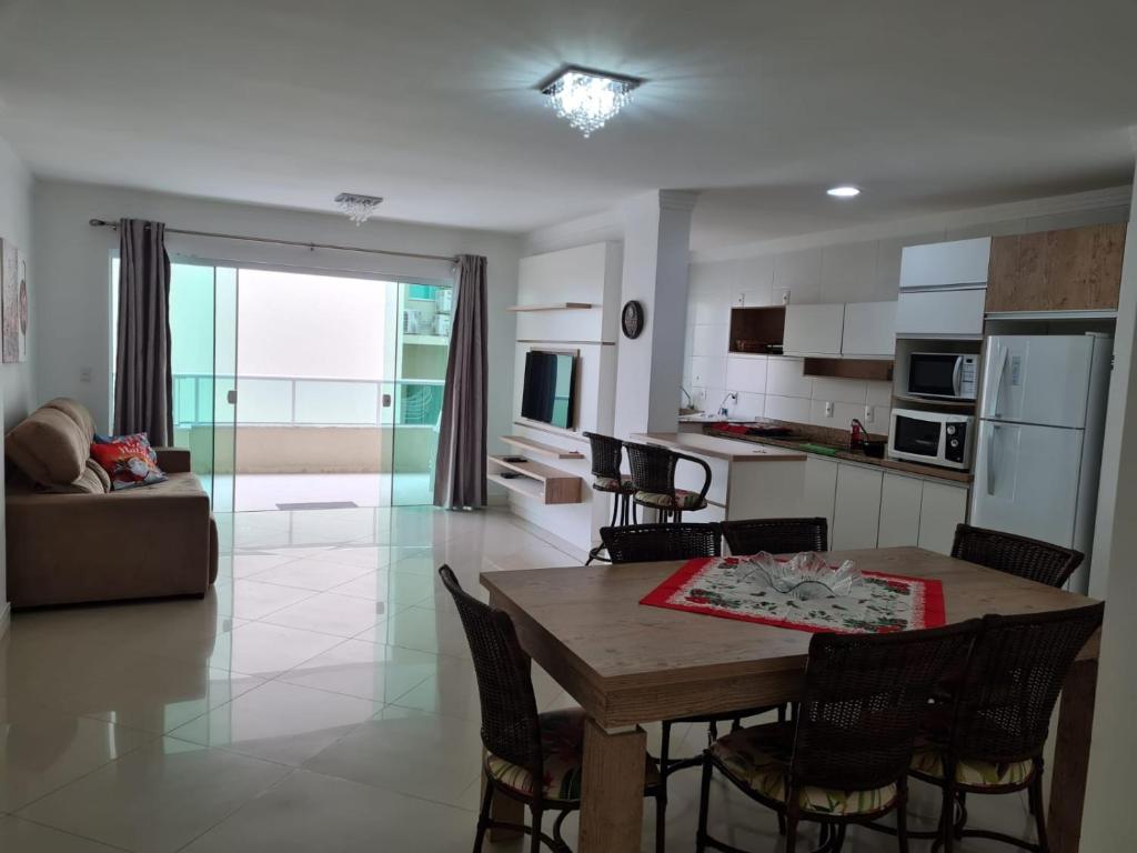 uma cozinha e sala de estar com mesa e cadeiras em Amplo e aconchegante apartamento com 3 quartos a 50m da praia de Bombas em Bombinhas