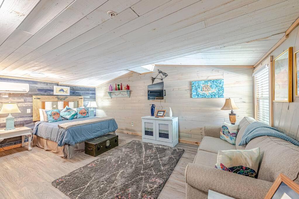 een slaapkamer met een bed en een bank in een kamer bij Something Fishy at Island Breeze of CB in Carolina Beach
