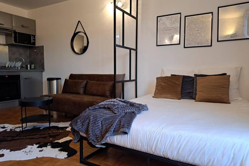 a bedroom with a bed and a couch and a mirror at L'industriel - 2'mn du métro - aux portes de Paris in Saint-Mandé