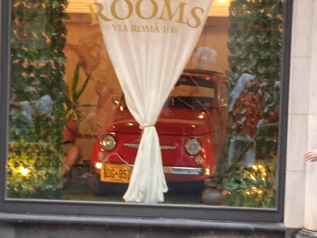 een reflectie van een rood busje in een raam bij via ROMA 100 ROOMS in Enna