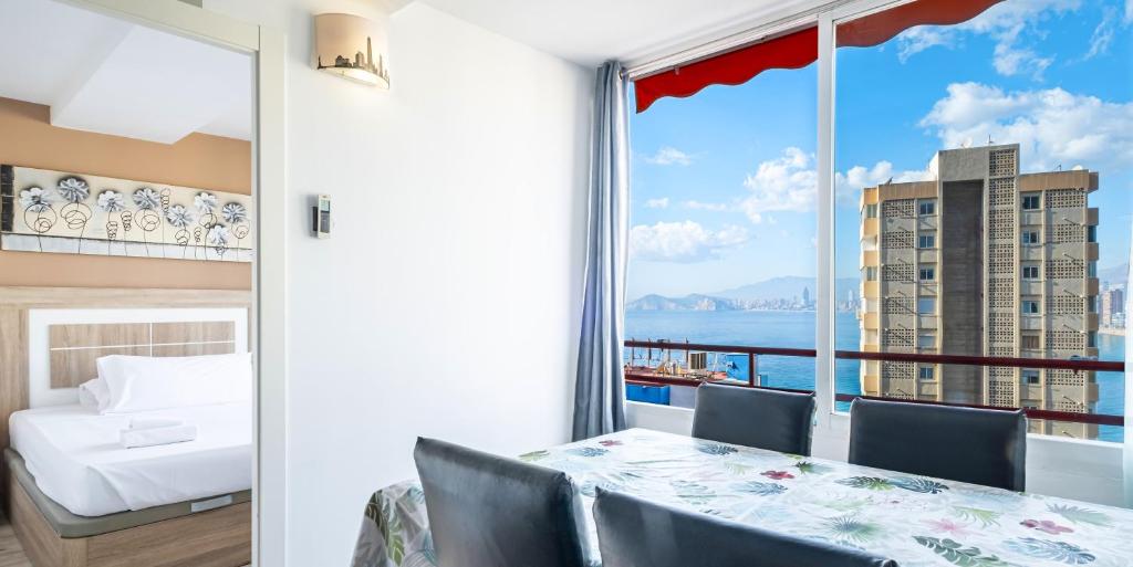 a bedroom with a table and a view of the ocean at Don Miguel 4-F Apartment Levante Beach in Benidorm
