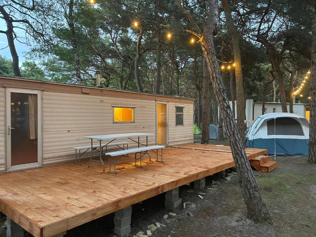 Cabaña con mesa y bancos en una terraza de madera en Your Caravan Hel, en Hel