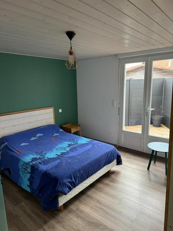 een slaapkamer met een blauw bed en een raam bij La Villa in Meschers-sur-Gironde