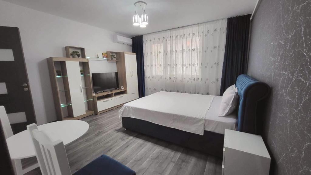 a bedroom with a bed and a table and a tv at Garsoniera NAVI in Onești