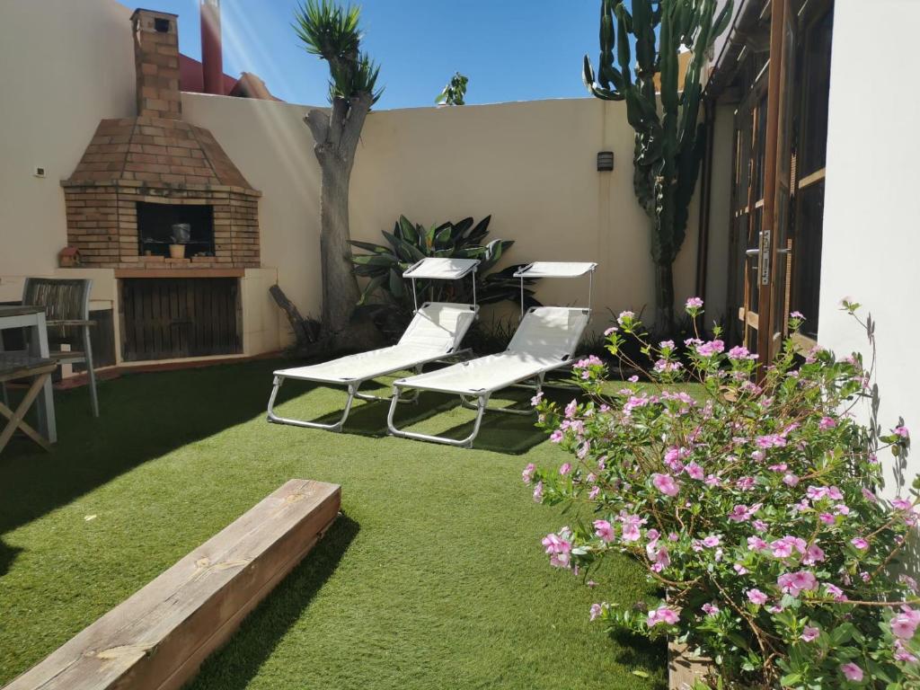 een patio met 2 witte stoelen en een open haard bij Casa La Buena Ola in Playa del Hombre