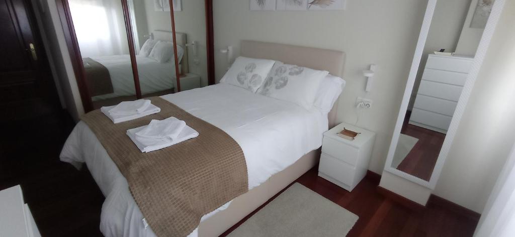 a small bedroom with a white bed with a mirror at Val do Fragoso in Vigo
