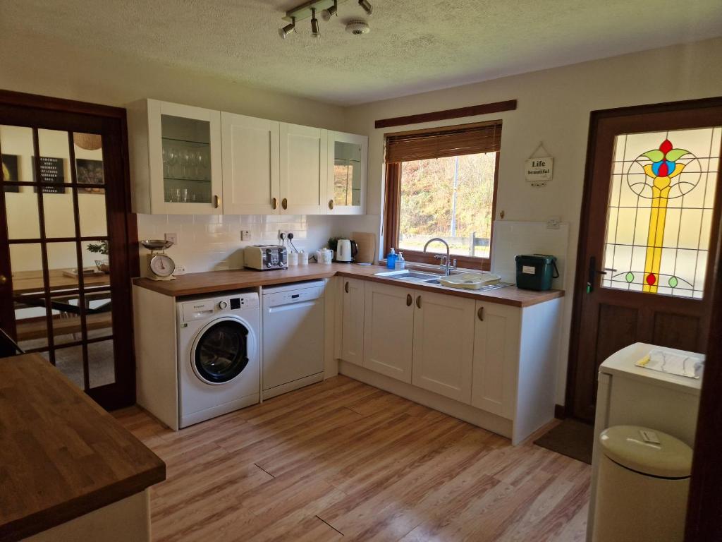 uma cozinha com uma máquina de lavar roupa e uma máquina de lavar roupa em Wilmar Lodge em Arrochar