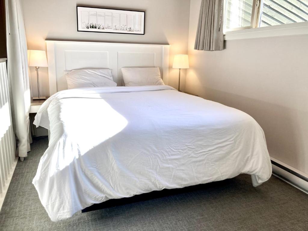 1 cama blanca grande en un dormitorio con ventana en Oceanfront Loft - amazing views! en Qualicum Beach