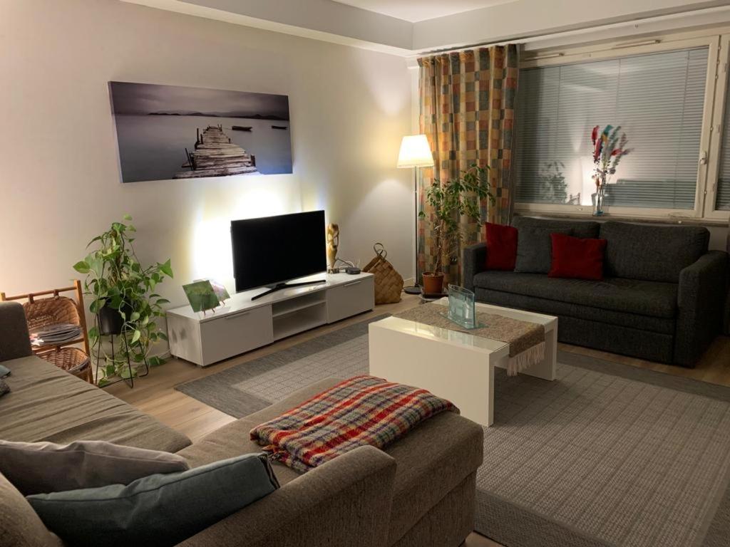 ein Wohnzimmer mit einem Sofa und einem TV in der Unterkunft Rovaniemi city Apartment in Rovaniemi