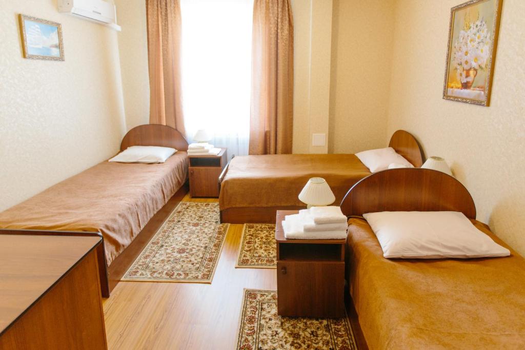 pokój hotelowy z 3 łóżkami i oknem w obiekcie Hotel Grand Tambov w mieście Tambow