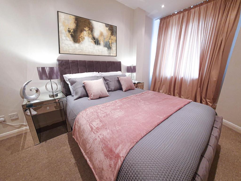 um quarto com uma cama grande e almofadas cor-de-rosa em Camden Elegance : Cozy&Modern (10 min to center) em Londres