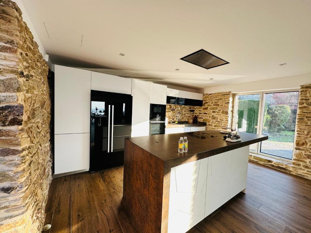 a kitchen with white cabinets and a stone wall at Casa familiar vista Rías in Vigo