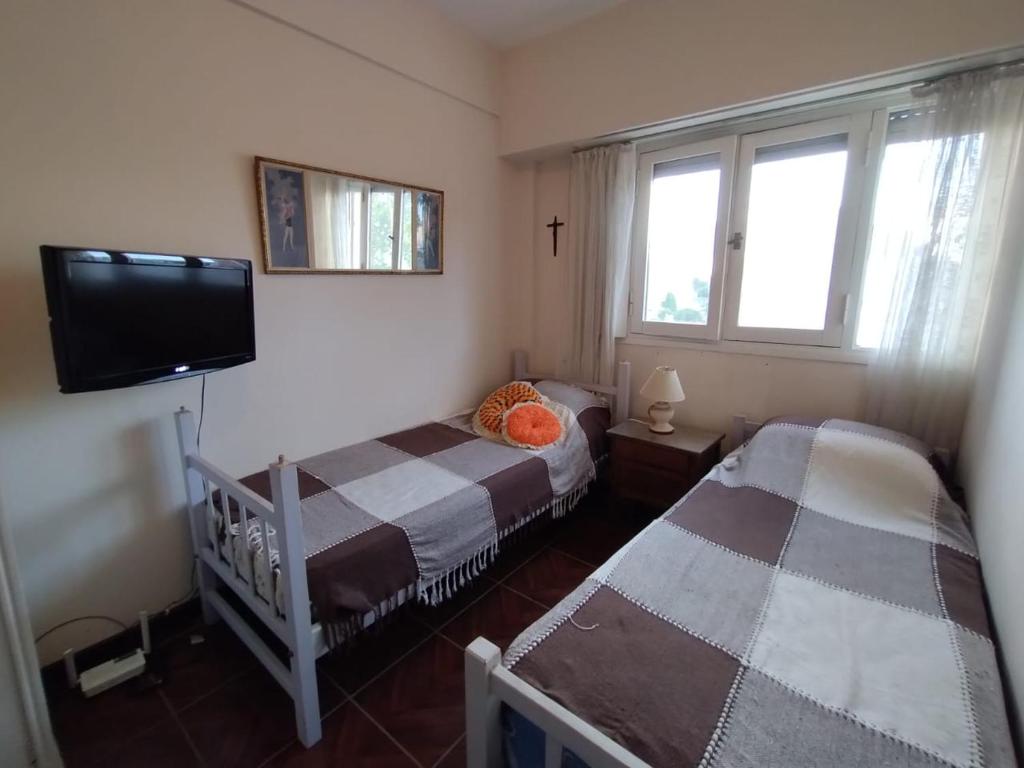 a bedroom with two beds and a flat screen tv at Namoro alojamientos in Mar del Plata