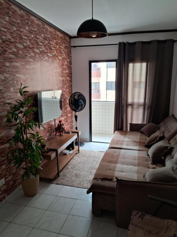 - une chambre avec un lit et un mur en briques dans l'établissement Apto Aconchegante, à Praia Grande