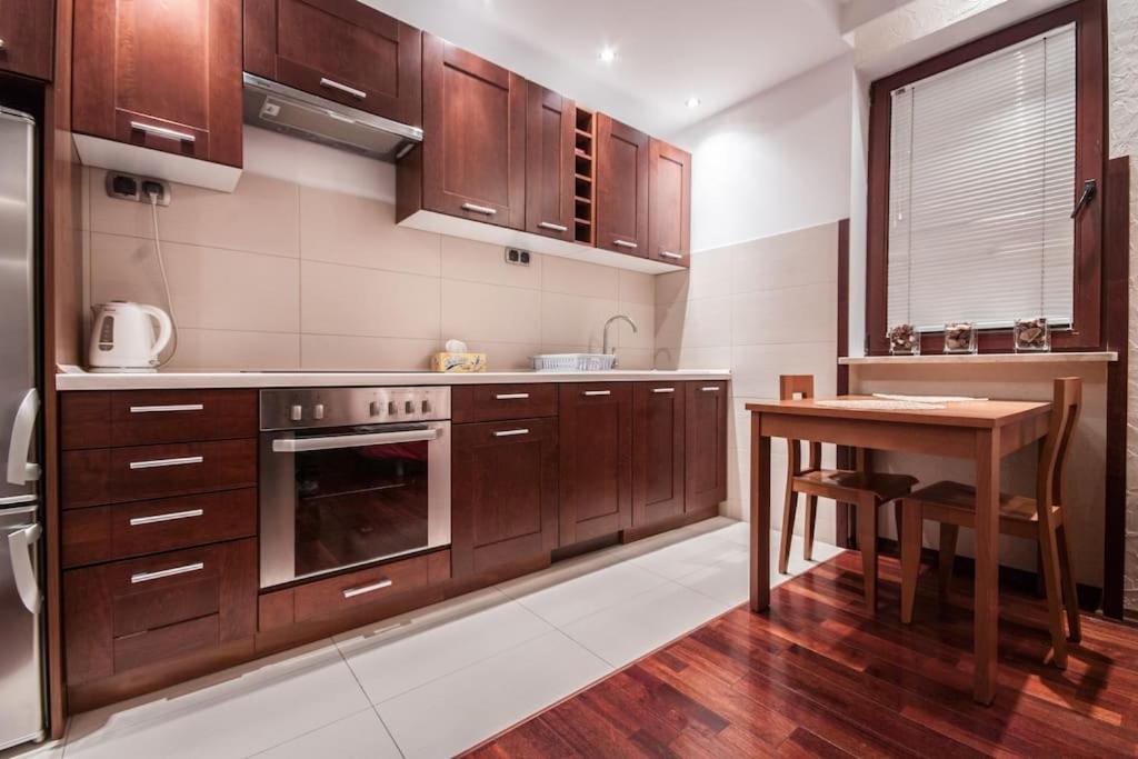 a kitchen with wooden cabinets and a wooden table at Superior Center 2 Rooms! Parking! Reception24h! in Warsaw