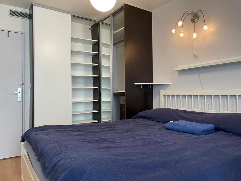 een slaapkamer met een groot bed en een blauwe deken bij Room cosycosy in Clichy