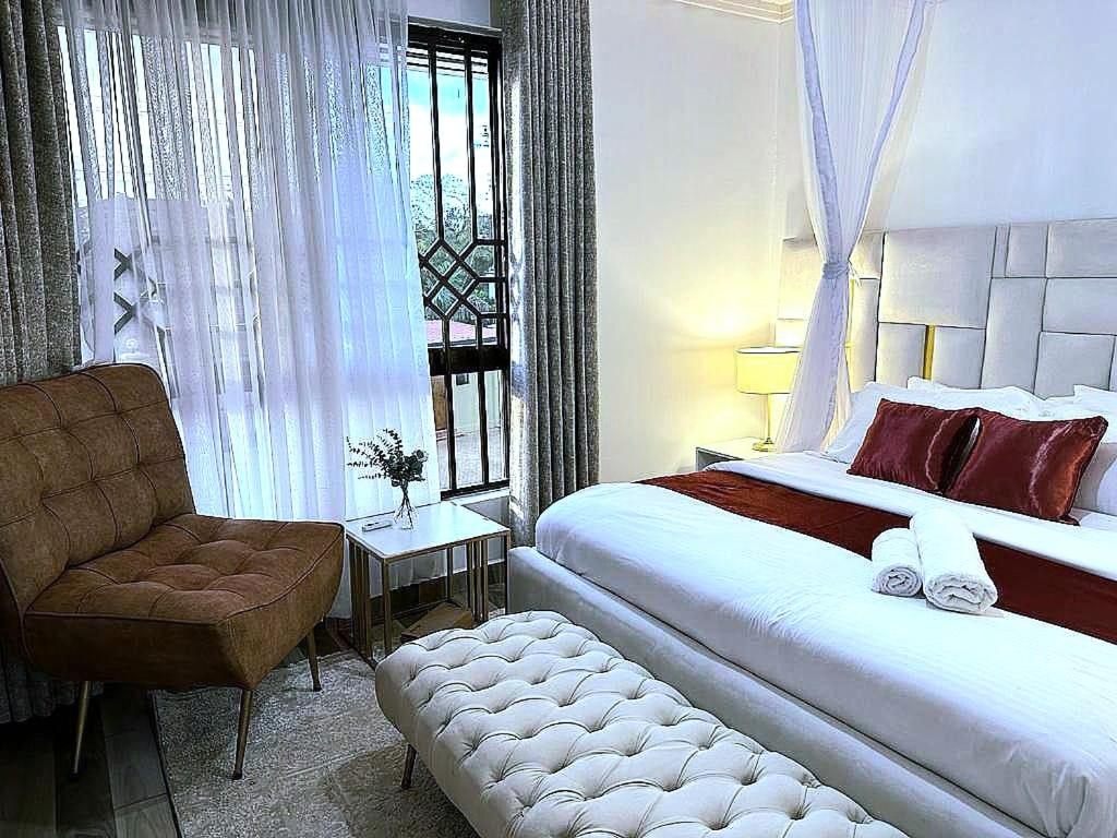 - une chambre avec un grand lit et une chaise dans l'établissement 3 BDR Luxurious Villa in Milimani Kisumu, à Kisumu