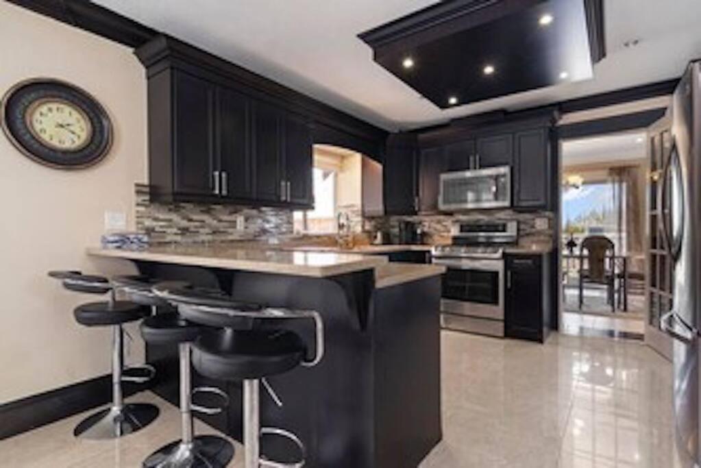 a kitchen with black cabinets and a clock on the wall at Cozy Home with a View on Acre in Abbotsford