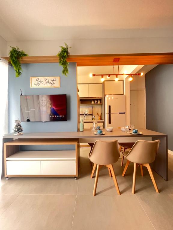een keuken met een tafel en twee stoelen en een televisie bij Apartamento prox shopping atlântico BrisamarBC5 in Balneário Camboriú