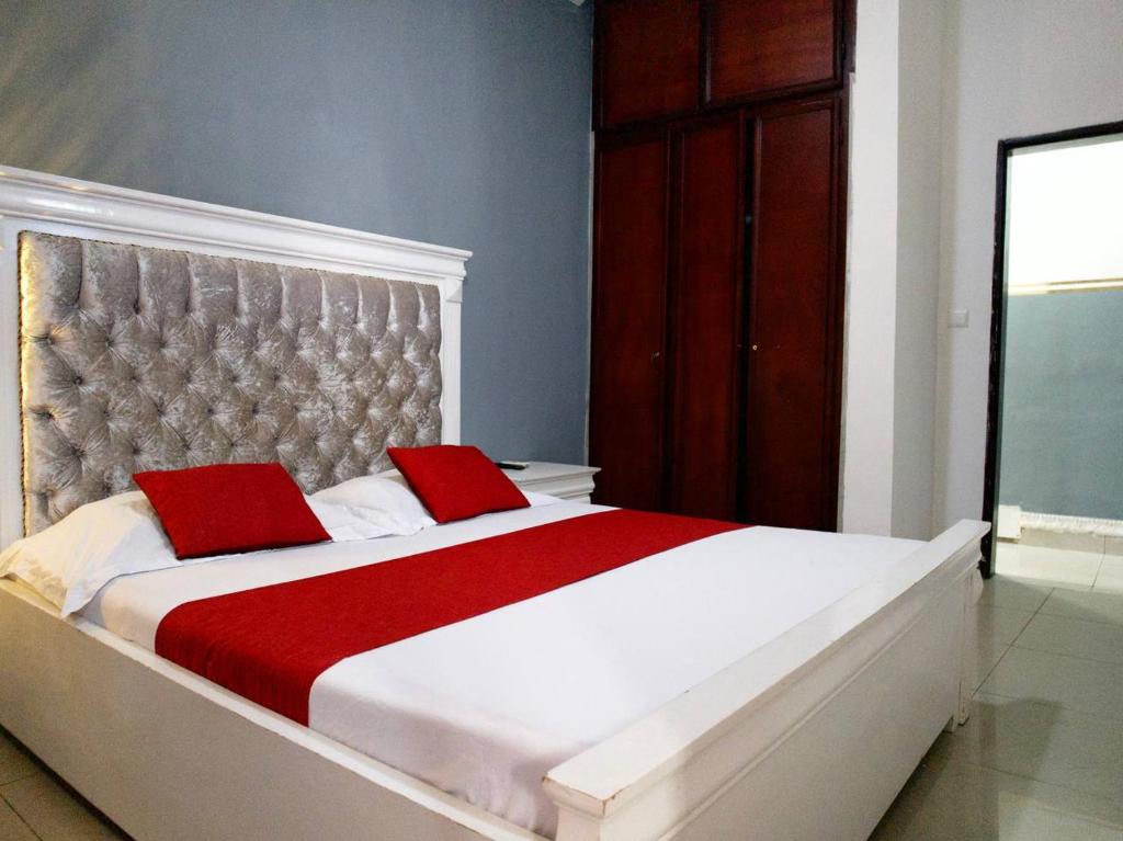 a bedroom with a large bed with two red pillows at Apparts meublés Tigson in Yaoundé