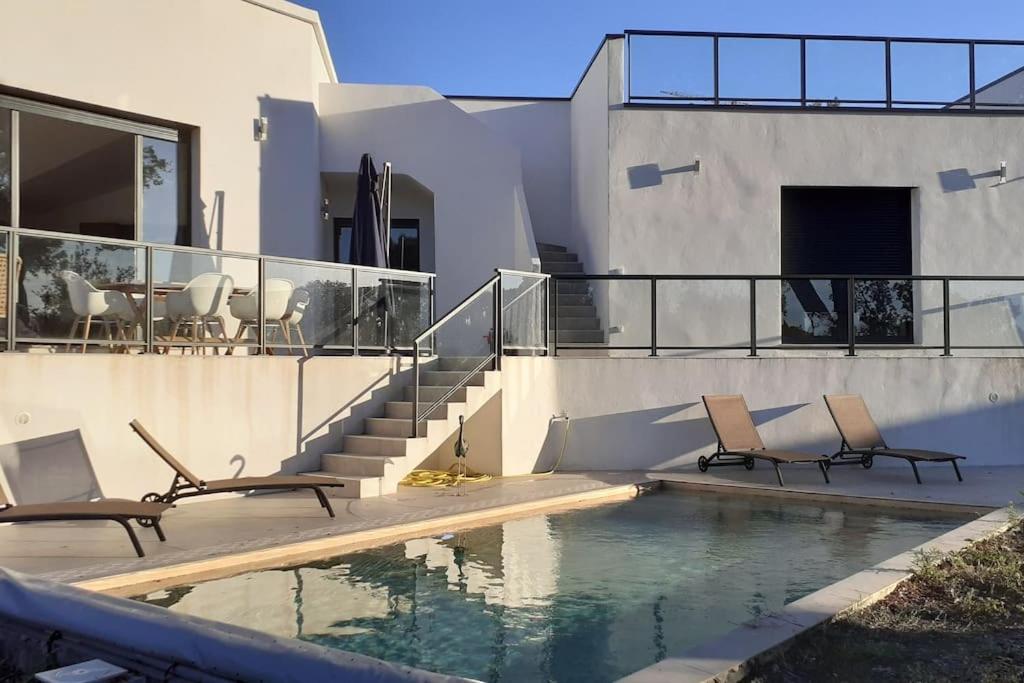 une maison dotée d'une piscine avec des chaises et une table dans l'établissement Villa Rossa Contemporaine Piscine chauffée, à Palasca