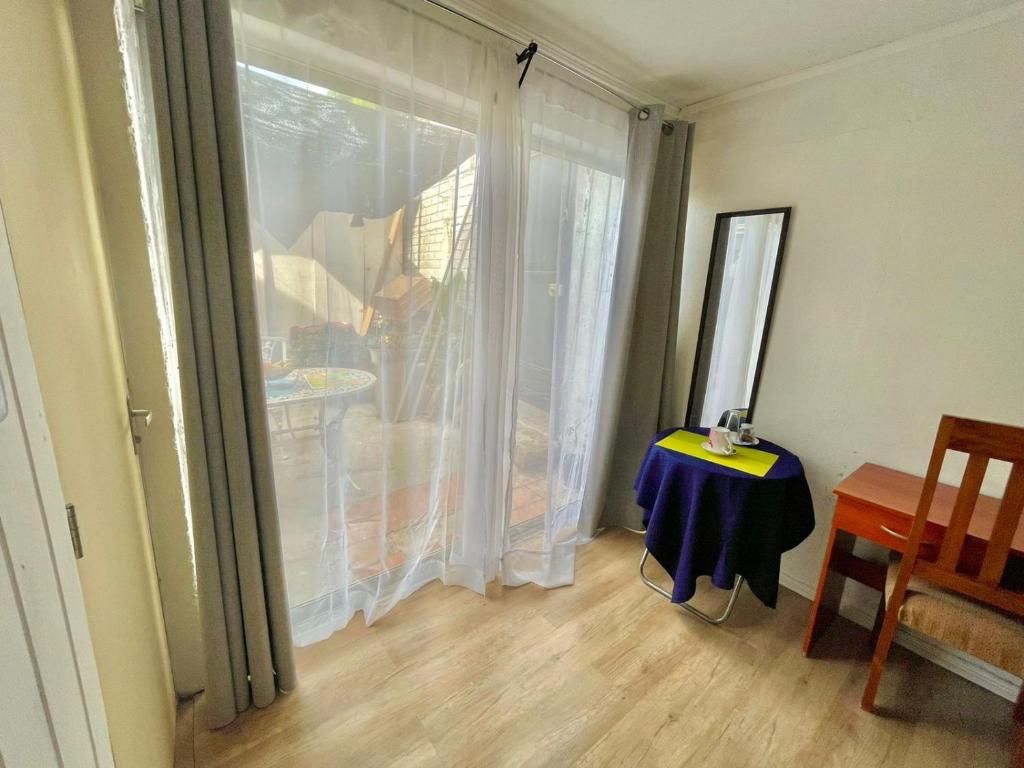 um quarto com uma porta de vidro deslizante com uma mesa e uma janela em Hostal Dulces Sueños em Chillán