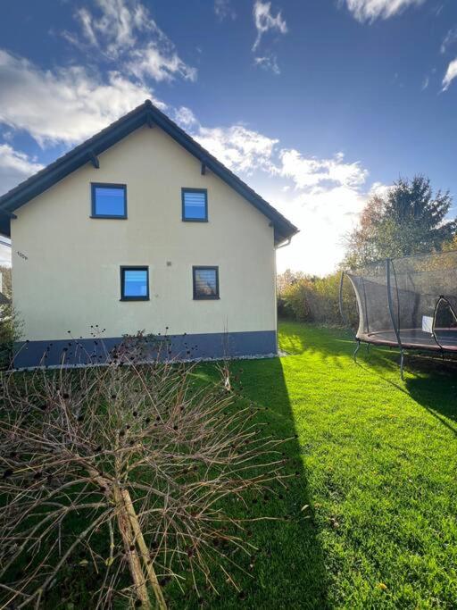 a white house in a yard with a boat at Schöne Ferienwohnung im Grünen in Hainichen
