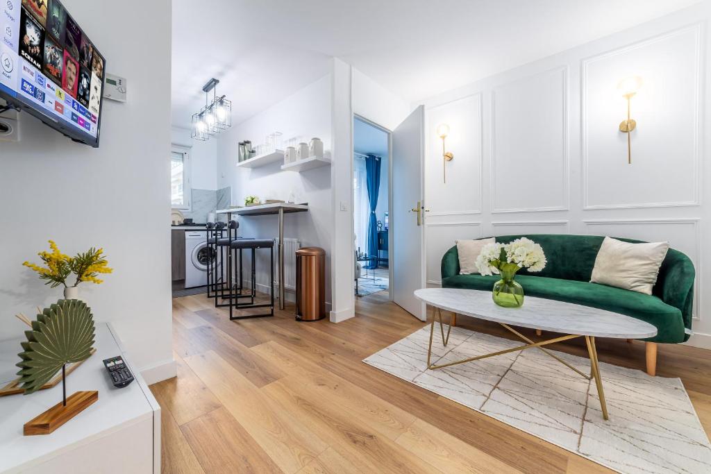 a living room with a green couch and a table at Appartement en face gare d'Evry - Proche Paris & Disney - Easy check in - Arrivée autonome -Place de parking privative - Wifi in Évry-les-Châteaux