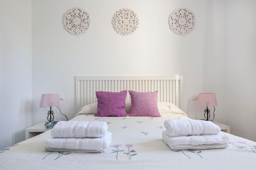 1 dormitorio con cama blanca y almohadas moradas en Adosado Cigüeñas IV-Islantilla Golf, en Huelva
