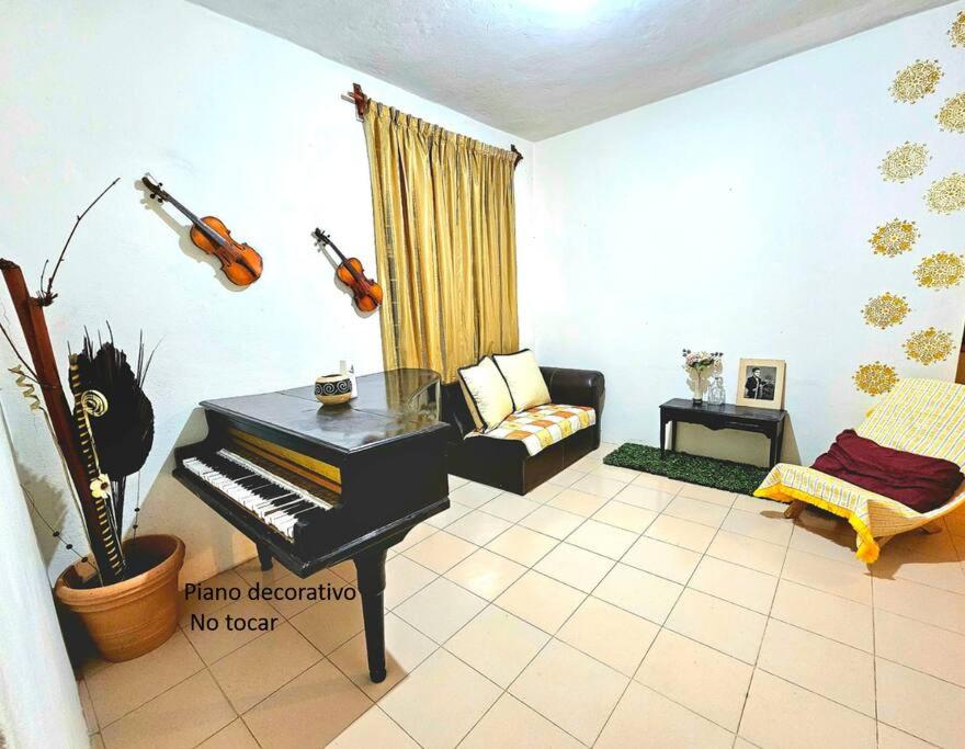 een woonkamer met een piano en een bank bij Escapada Delicias Oaxaqueñas in Santa Cruz Xoxocotlán