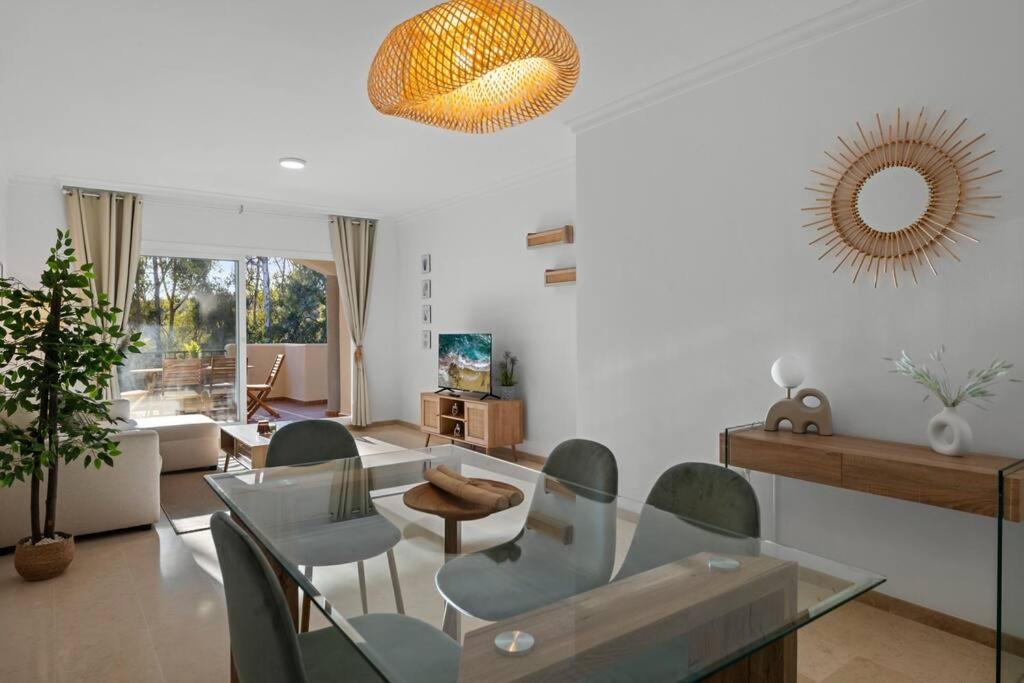 uma sala de estar com uma mesa de vidro e cadeiras em Luminoso apartamento en Elviria em Marbella
