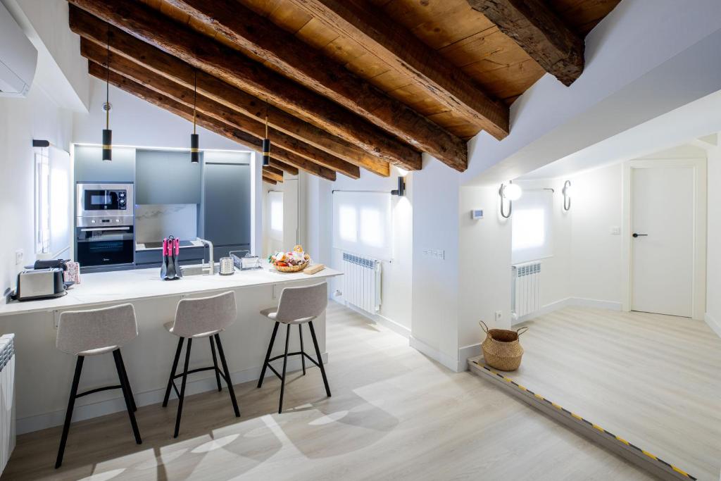uma cozinha com paredes brancas e um bar com bancos em Apartamentos Hartzenbusch em Teruel