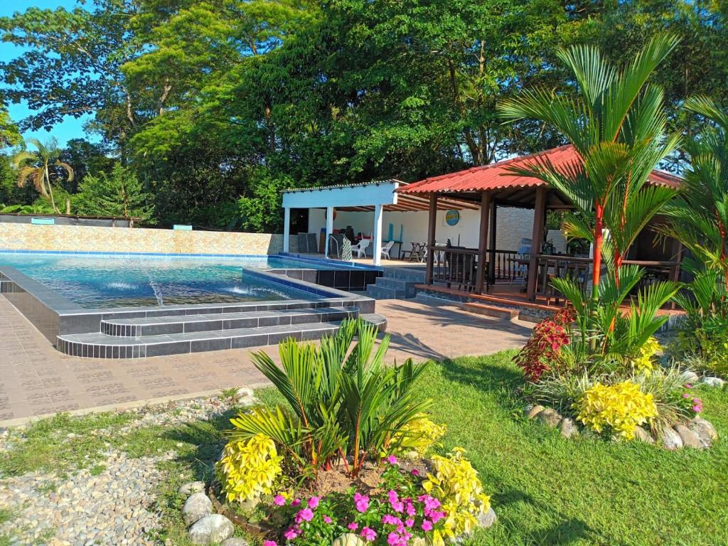 una piscina con cenador y flores en HOSPEDAJE FAMILAR CAMPESTRE "Villa Alondra", en Villavicencio