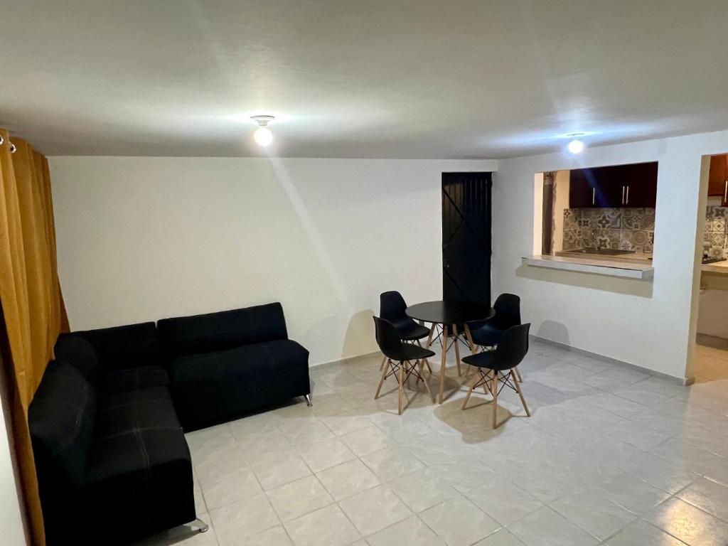 ein Wohnzimmer mit einem schwarzen Sofa und Stühlen in der Unterkunft Departamento Doña Maryy in Tampico