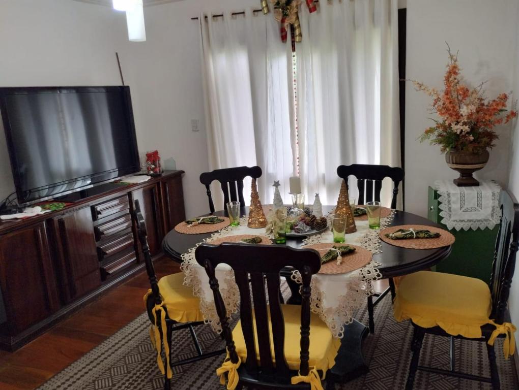 een eetkamer met een tafel met stoelen en een televisie bij Casa aconchegante Gramado em local tranquilo- 5 km do centro locação temporada in Gramado
