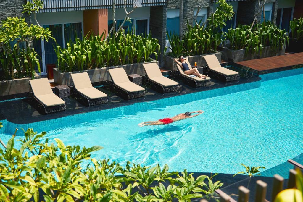 a man laying in a swimming pool at a hotel at Fairfield by Marriott Bali Kuta Sunset Road in Kuta